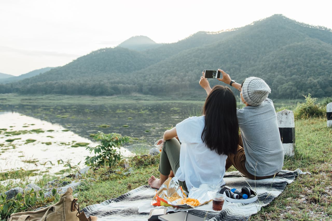 Couple on a picnic taking picture of mountain with a mobile device